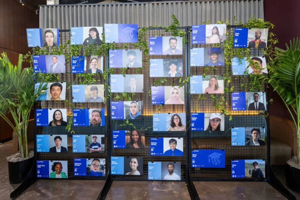Display of portraits with names and titles on a grid decorated with green vines.