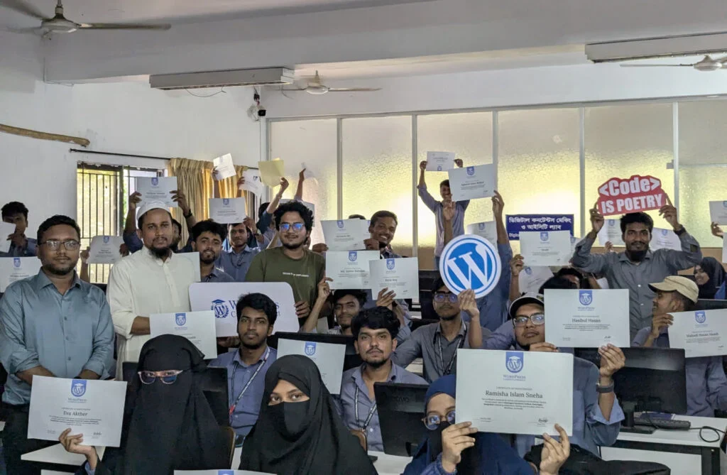 Group of people holding certificates and WordPress signs in a classroom.