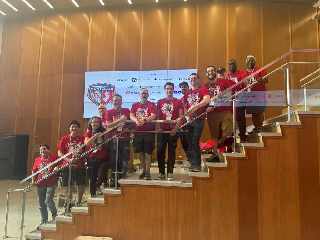 Group in red WordCamp Montclair shirts posing on a staircase.